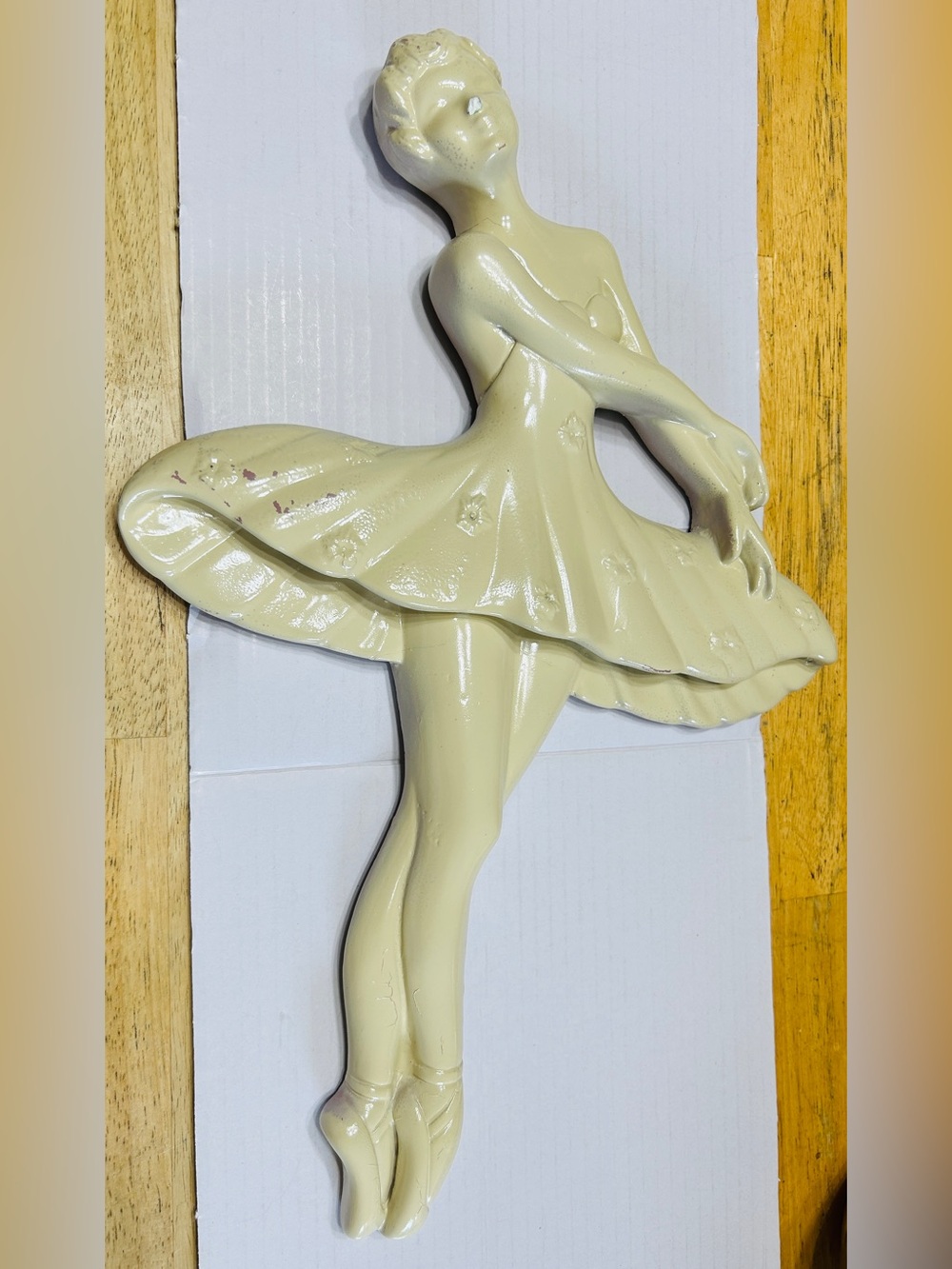 Chalk ware ballerina hangs on the wall.
